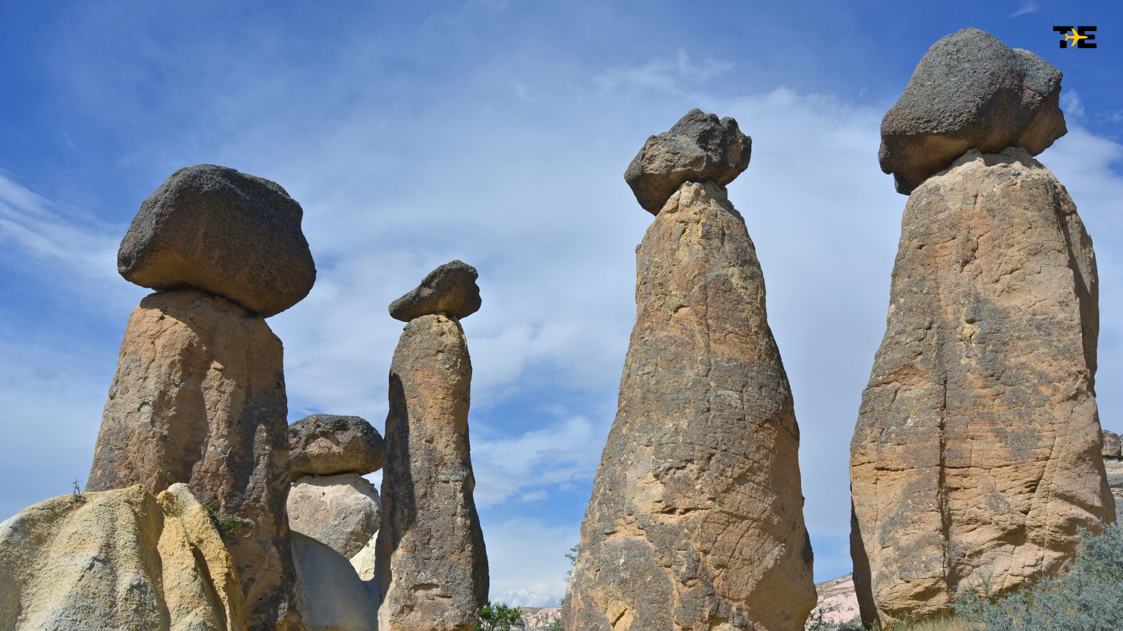 Breathtaking Cappadocia fairy chimneys with boulders atop ancient rock pillars under a vibrant sky.