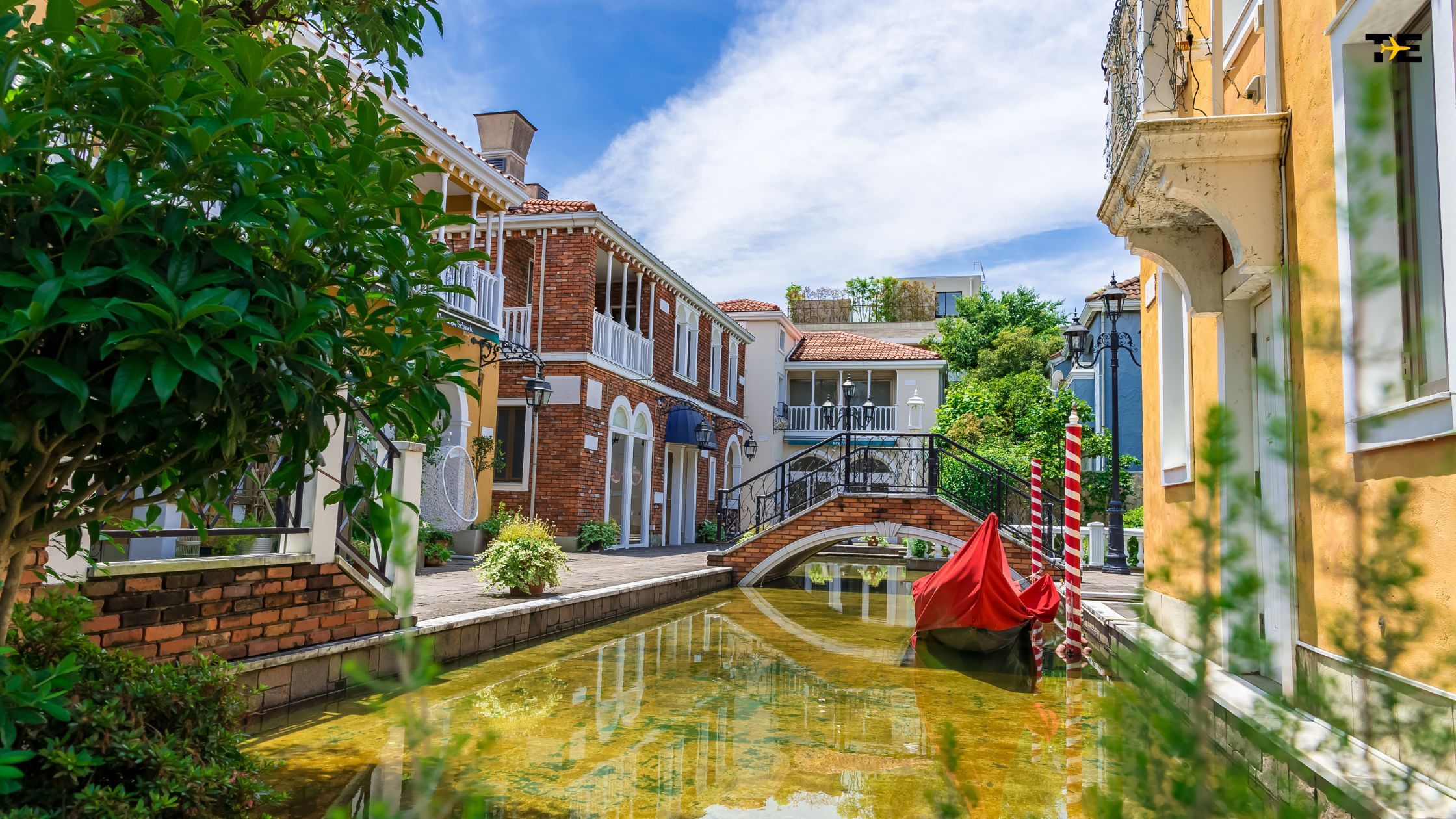 Charming canal scene with vibrant architecture, red boat, and serene greenery.
