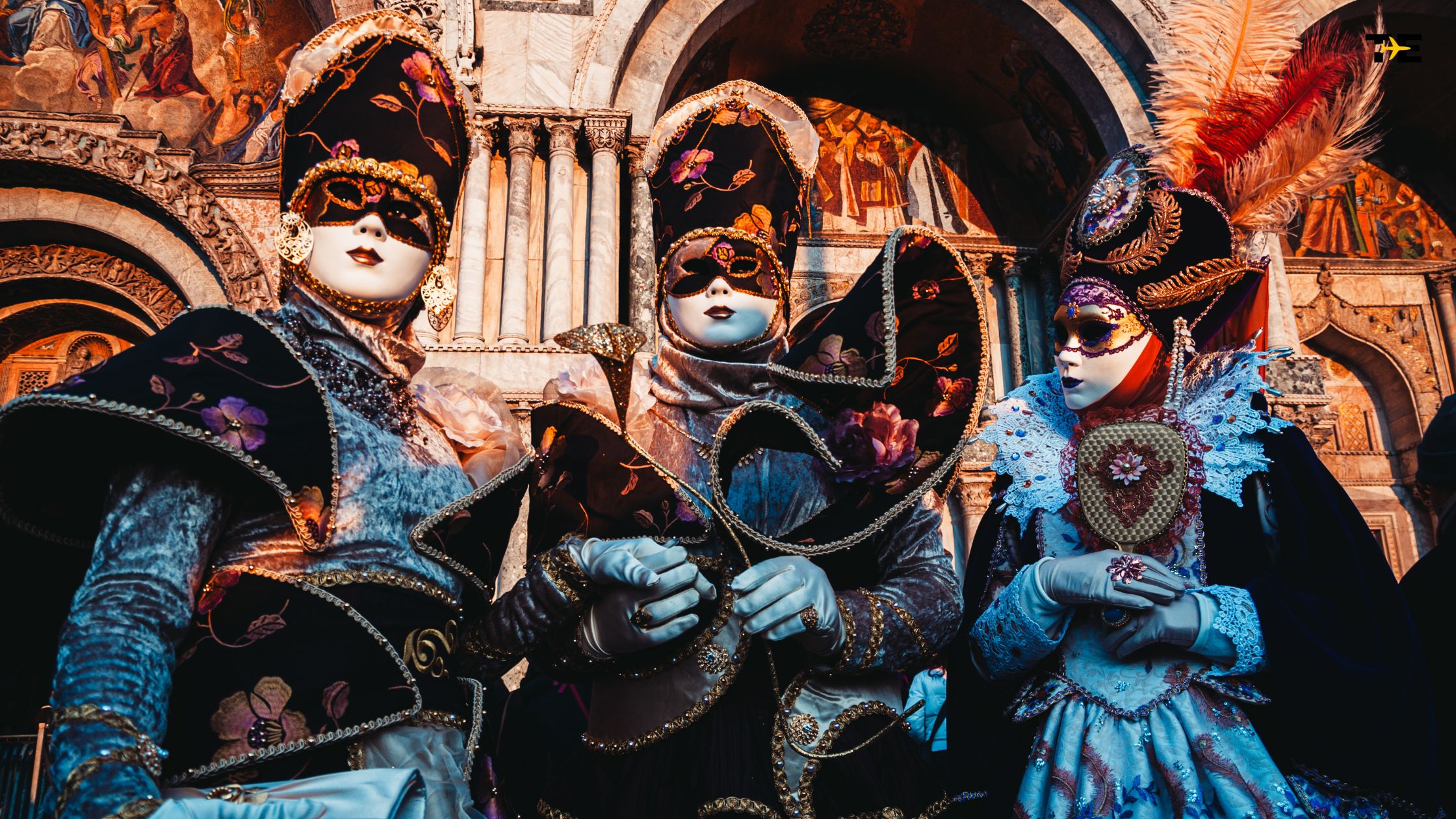 Elegant masked figures in elaborate carnival costumes at a vibrant masquerade ball.