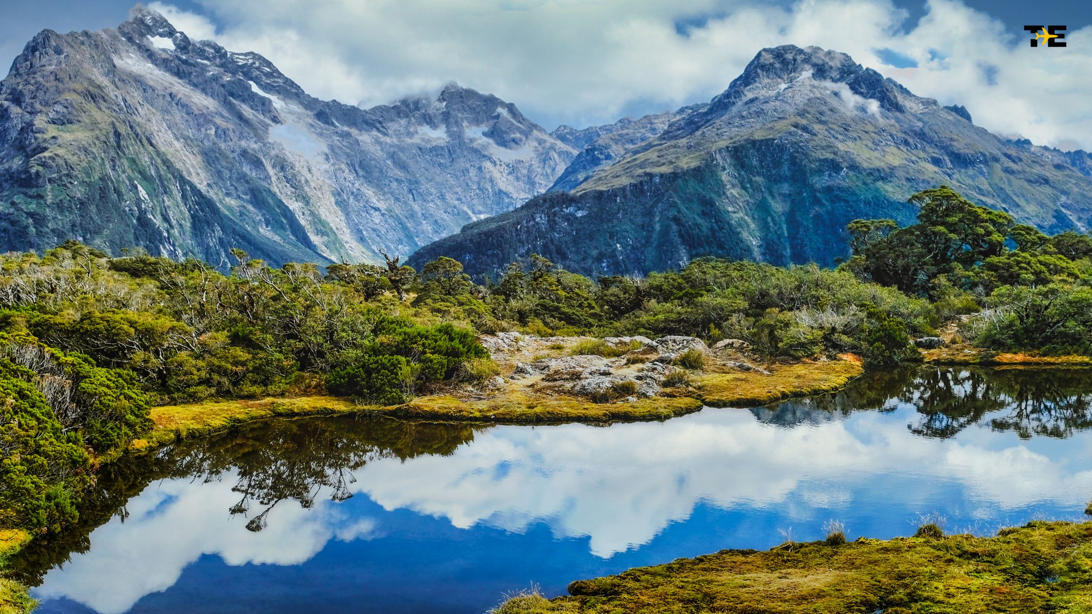 Majestic mountains reflect in a serene pond, showcasing breathtaking natural beauty and tranquility.