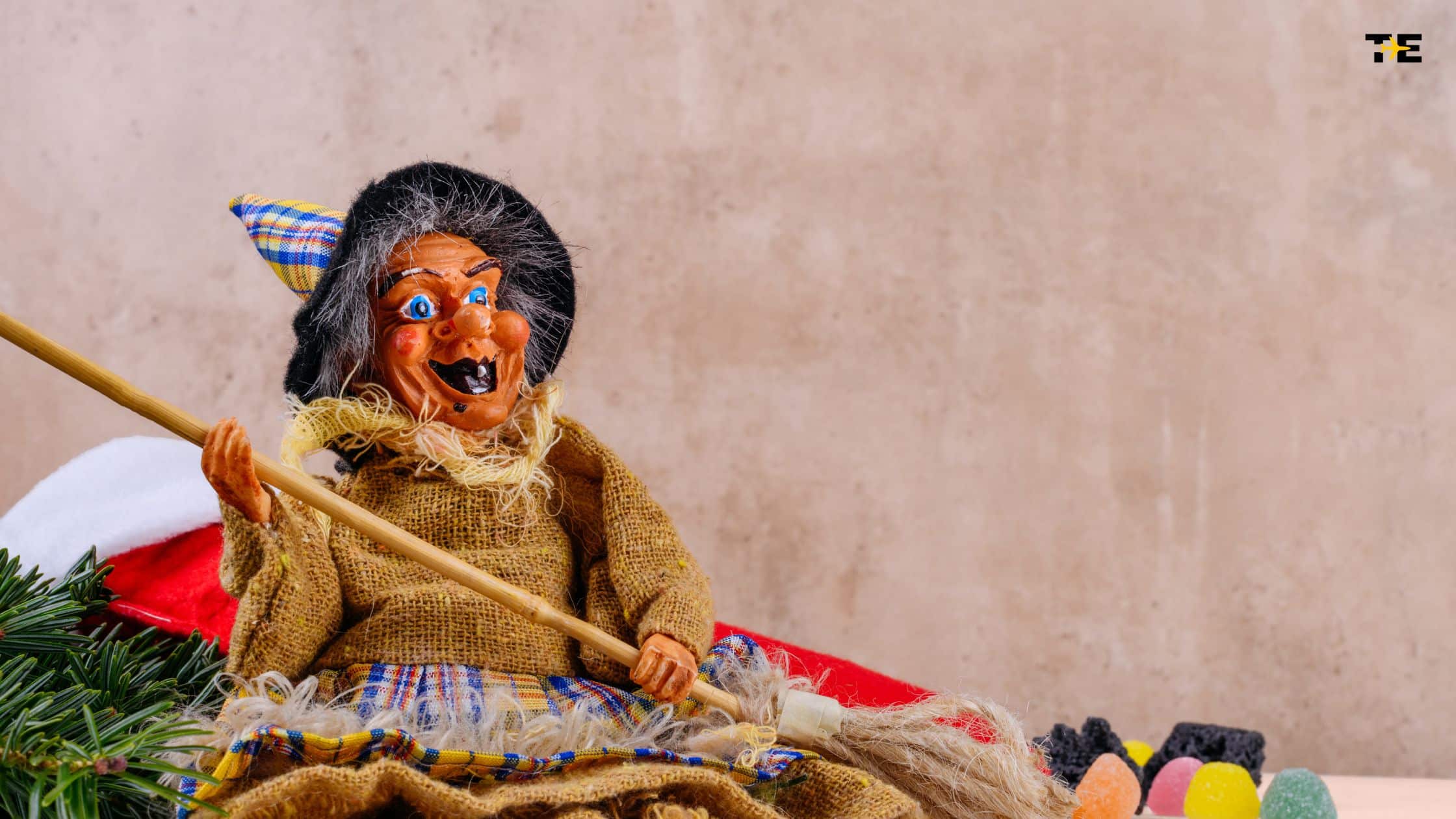 Colorful whimsical witch doll with vibrant attire and broomstick, perfect for festive decor.